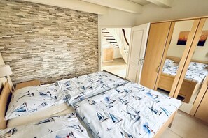 A bedroom with a bed, a wardrobe, and a brick wall. - Friesengeist Country House (Greetsiel)
