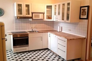 A kitchen with white cabinets, a microwave, an oven, and a sink. - Holiday apartment in Borkum with barbecue (Borkum)