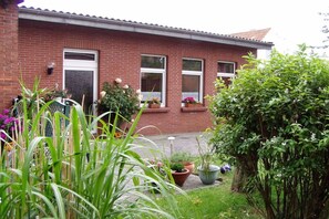 A brick house with a front garden, potted plants, and a small tree. - Holiday apartment in Borkum with barbecue (Borkum)