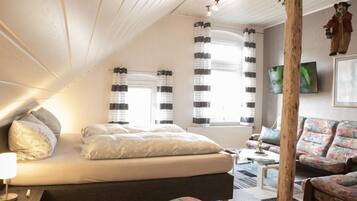 A bedroom with a bed, bedside table, and a large window with curtains.