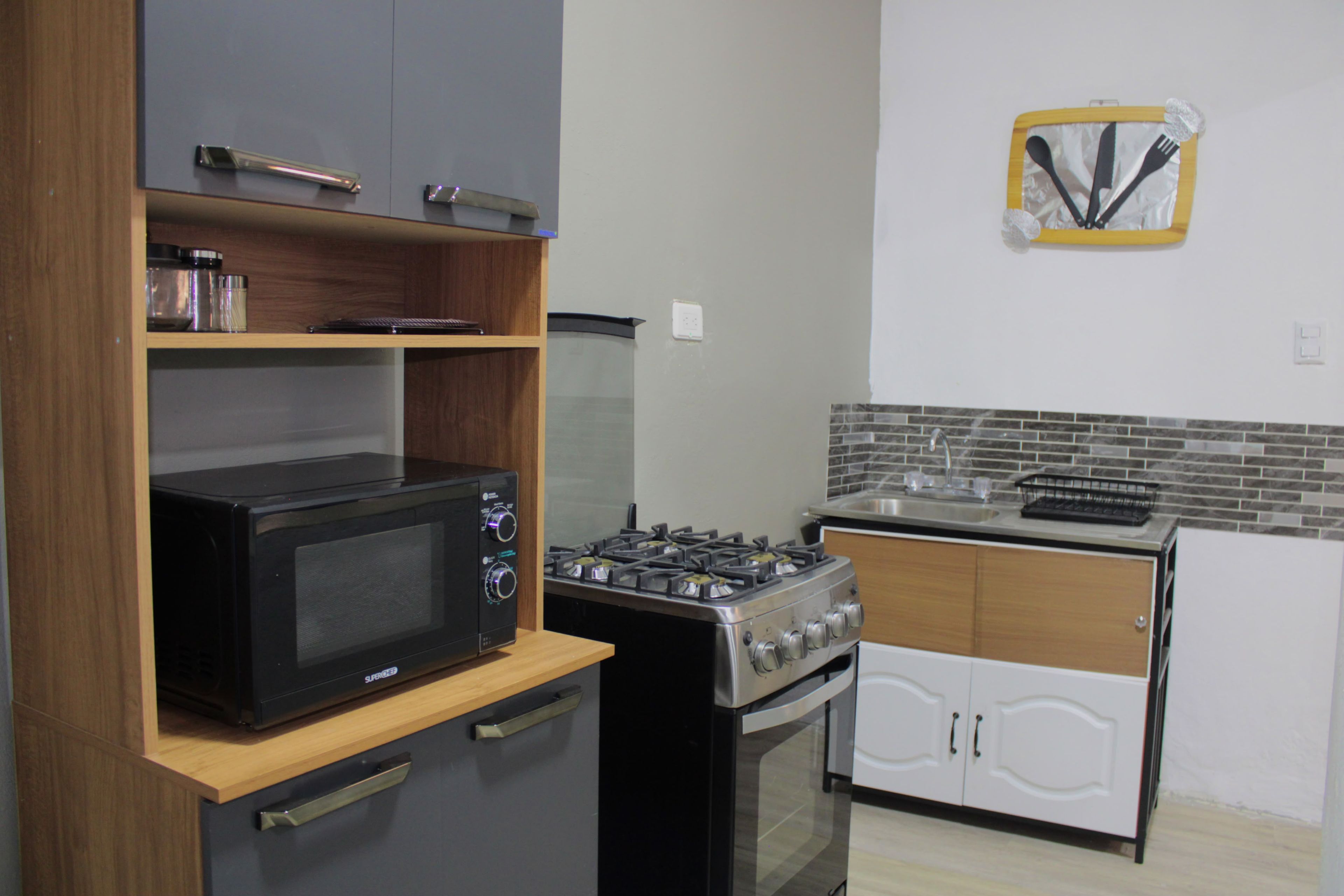 A compact kitchen with a microwave, stove, and a small refrigerator.