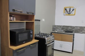 Cozinha compacta com micro-ondas, fogão e pequena geladeira.