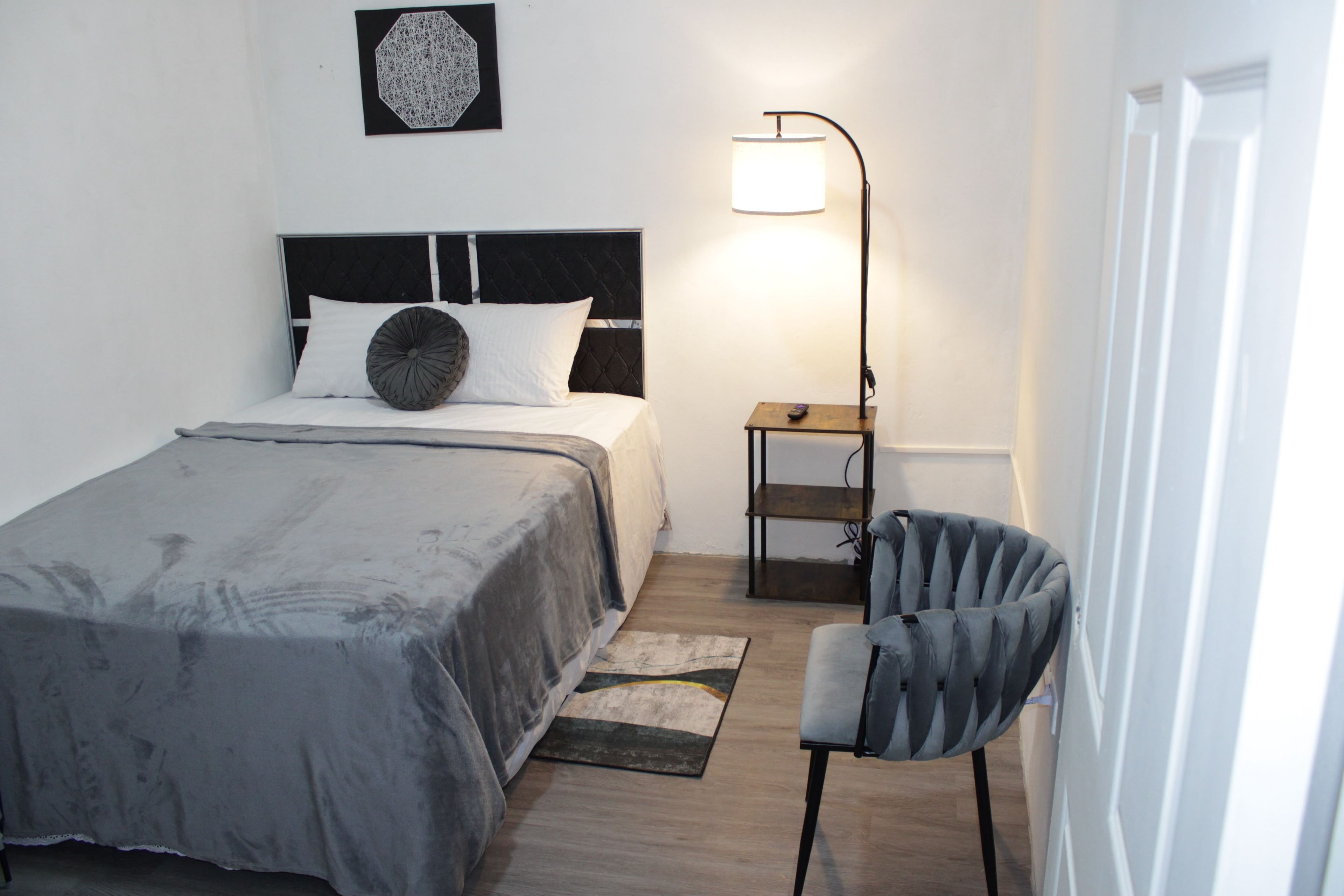 Ein Schlafzimmer mit einem Bett, einem Sessel, einem Nachttisch und einer Lampe.