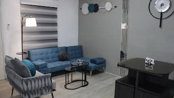 Un salon moderne avec un canapé d’angle, une petite table ronde et une horloge murale décorative.