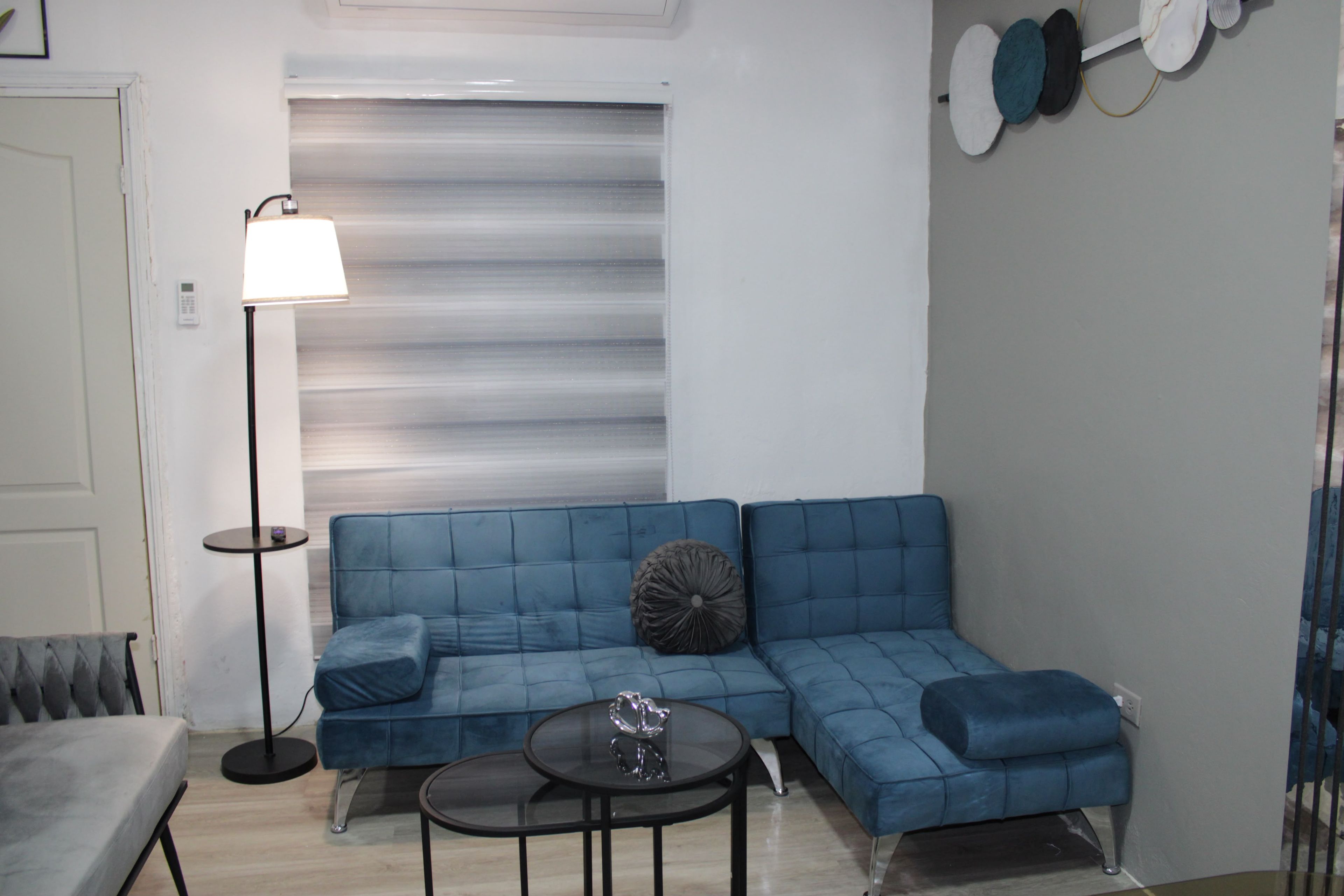 A modern living room with a blue sectional sofa, a small round coffee table, and a floor lamp.