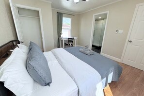 A hotel room with a bed, a desk, and a shower area.