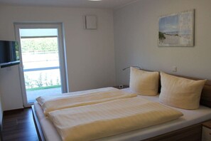 A bedroom with a bed, a television, a window, and a painting on the wall. - Holiday apartment with 1 bedroom (Krummhörn-Greetsiel)