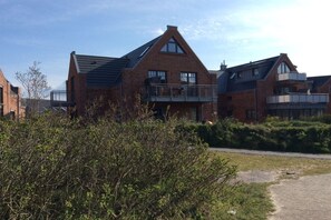 A modern brick house with a balcony, surrounded by greenery. - Holiday apartment with 2 bedrooms (Wangerooge)