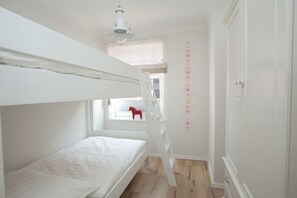 Een slaapkamer met een stapelbed, een raam met uitzicht en een kledingkast.
