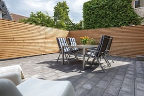 Eine Terrassengruppe im Freien mit Holzzaun, zwei Tischen mit Stühlen und einem Topfpflanzen.