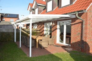Un patio techado con mesa y sillas, una casa de ladrillo y un vidrio.