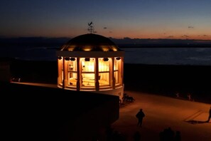 Un edificio circular con techo abovedado, posiblemente un faro o torre de observación, con vista al mar de fondo.
