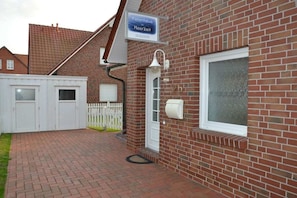 A brick building with a sign indicating a business, a white door, and a mailbox. - MeerZeit - Süderpfad 2b (Borkum)