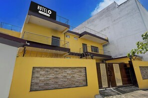 A hotel with a prominent sign, a gated entrance, and a balcony with a metal railing. - Super Hotel O Samne Ghat (Varanasi)