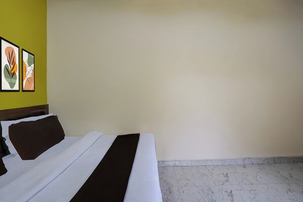 A hotel room with a bed, a headboard, a wall with two framed pictures, and a marble floor. - Super Hotel O Samne Ghat (Varanasi)