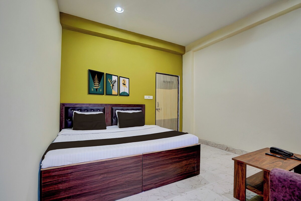 A hotel room with a bed, a bedside table, a chair, and a door.