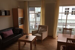 Ein Wohnzimmer mit einer Couch, einem Sessel, einem Couchtisch und einem Esstisch.