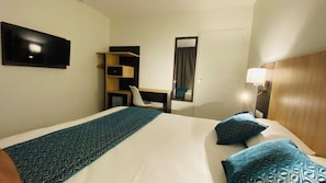 A hotel room with a bed, a desk, a chair, and a wardrobe. - Appart'hôtel Martinez (Grenay)
