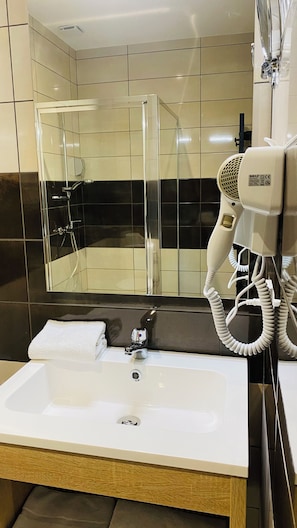 A bathroom with a shower, a sink, and a hairdryer. - Appart'hôtel Martinez (Grenay)