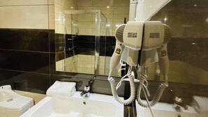 A bathroom with a white sink, a mirror, and a hairdryer mounted on the wall. - Appart'hôtel Martinez (Grenay)