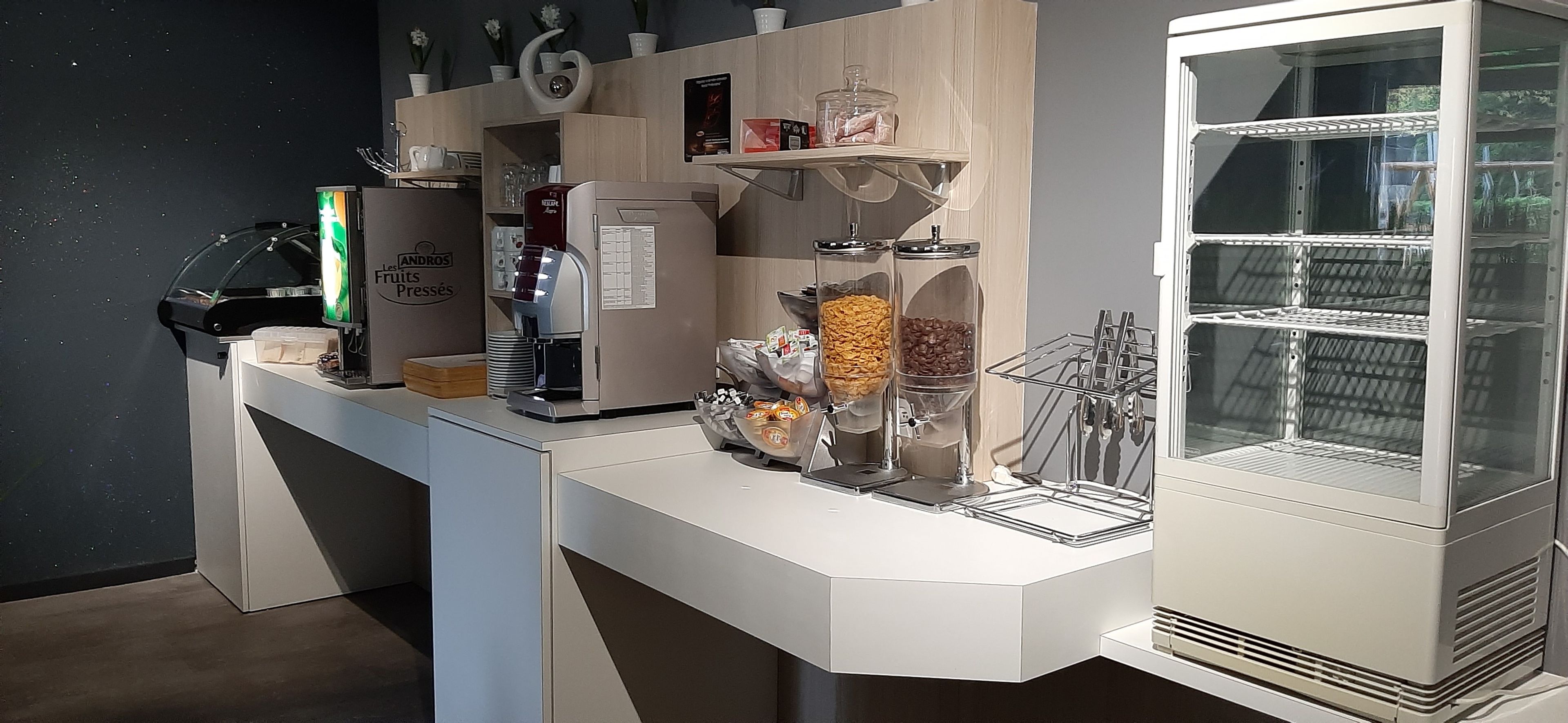 Una cocina moderna con cafetera, refrigerador y vitrina de vidrio.