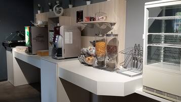 Una cocina moderna con cafetera, refrigerador y vitrina de vidrio.