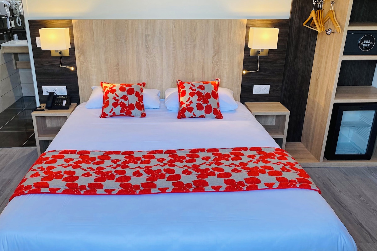 A hotel room with a large bed, two bedside lamps, a minibar, and a small refrigerator.