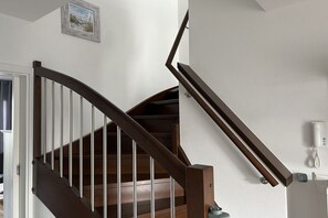 A wooden staircase with a handrail, a door leading to another room, and a wall-mounted phone. - Holiday apartment with 1 bedroom (Norderney)