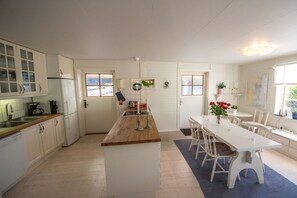 A kitchen with white cabinets, a wooden countertop, and a dining area with a white table and chairs.