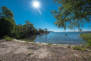 A natural landscape with a body of water, trees, and a clear sky.