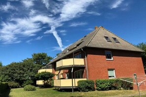 A two-story building with a red brick facade, a flat roof, and a balcony on the upper floor. - Holiday apartment on Damenpfad (Wangerooge)