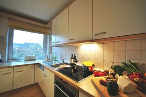 A kitchen with a window, a stove, and various food items on the counter. - Holiday apartment on Damenpfad (Wangerooge)