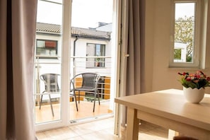 A room with a sliding glass door leading to an outdoor balcony with two chairs and a table. - One-bedroom guesthouse in Poland (Grzybowo \/ Kolberg)