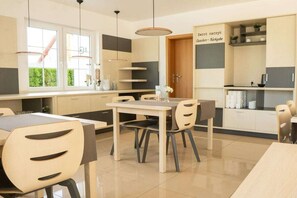 Una cocina moderna con comedor, que cuenta con un amplio ventanal, luces colgantes y muebles empotrados.