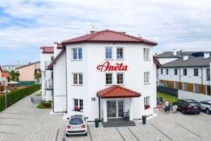 Un edificio blanco con techo rojo y el nombre 'Aneta' en letras rojas.