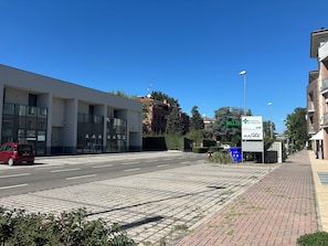 A street view with a modern building, a clear sky, and a sign for a pharmacy. - Bright & comfortable apartment in Carpi—your perfect base for exploring Italy (Carpi)