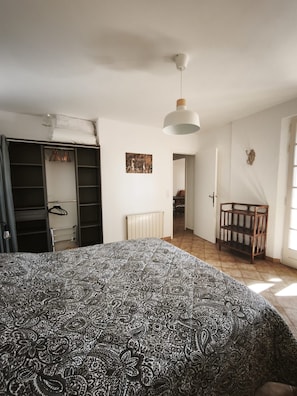 Ein Schlafzimmer mit einem Bett, einem Kleiderschrank, einem Heizkörper und einer Tür zu einem anderen Raum.