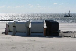 Une plage de sable avec plusieurs petites structures blanches en forme de tente.