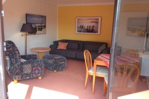 A living room with a sofa, armchairs, a small table, and a chair. - Holiday apartment with 2 bedrooms (Borkum)
