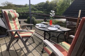 A balcony with a table, chairs, and a vase with flowers. - Holiday apartment with 2 bedrooms (Borkum)