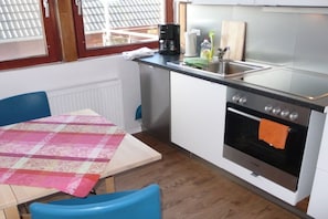 A compact kitchen with a table, chairs, a coffee maker, a sink, and an oven. - Holiday apartment with 2 bedrooms (Borkum)