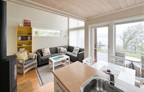 A cozy living room with a sofa, a coffee table, a bookshelf, and a view of the outdoors. - 3 bedroom gorgeous home in Moi (Moi)