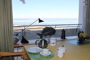 Ein Zimmer mit Blick auf den Strand, ein Tisch mit Tee-Service, eine Fischdekoration und eine Lampe.