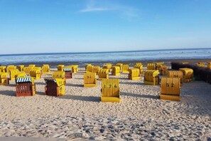 Ein Strand mit gelben, nummerierten Behältern und freiem Blick auf das Meer.