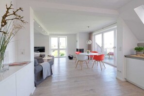 Ein zeitgemäßer Wohnbereich mit Essplatz, einer Couch und einem Fernseher.