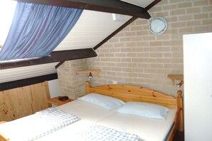 A room with a wooden bed, a brick wall, and a small shelf. - Holiday home with 3 bedrooms (Bruinisse)