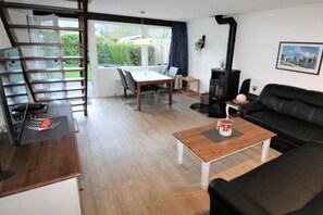 A furnished living room with a sofa, a table, a fireplace, and a staircase. - Holiday home with 3 bedrooms (Bruinisse)