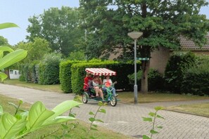 A paved pathway with a green carriage and a red and white striped canopy. - Holiday home with 3 bedrooms (Bruinisse)