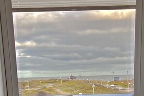 A view of a coastal area with a gazebo, flags, and a body of water. - The Captain's House by the Sea (Norderney)