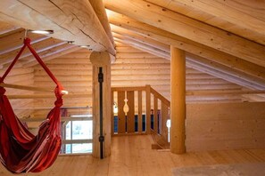 A wooden interior with a hammock, wooden beams, and a staircase. - Conny's Nature Mountain Hut (Grosskirchheim)